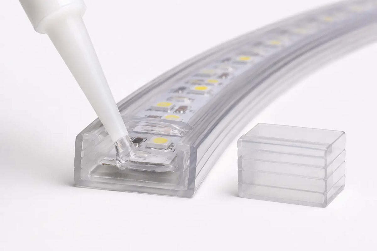 Transparentes Silikon wird in das offene Ende des 230-V-LED-Schlauchs gegeben, daneben liegt die passende Endkappe